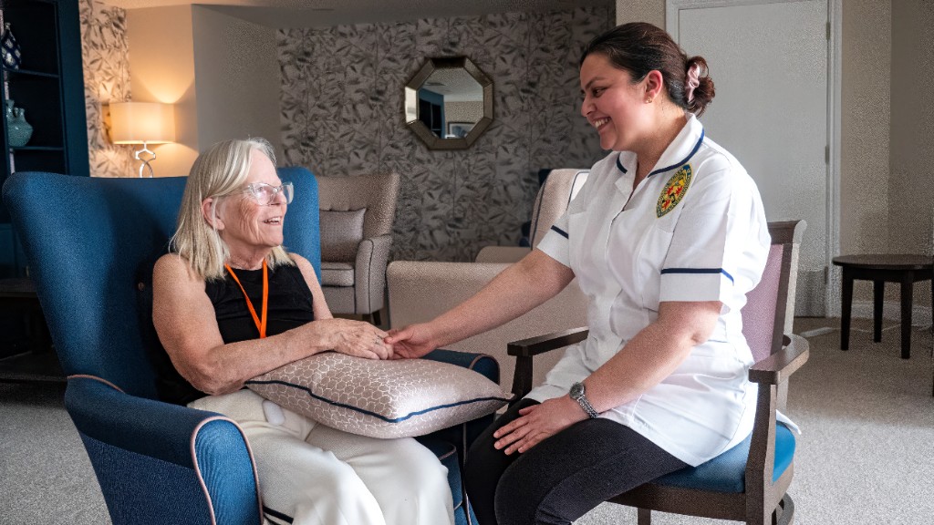 A member of the care team sitting with a resident at California House